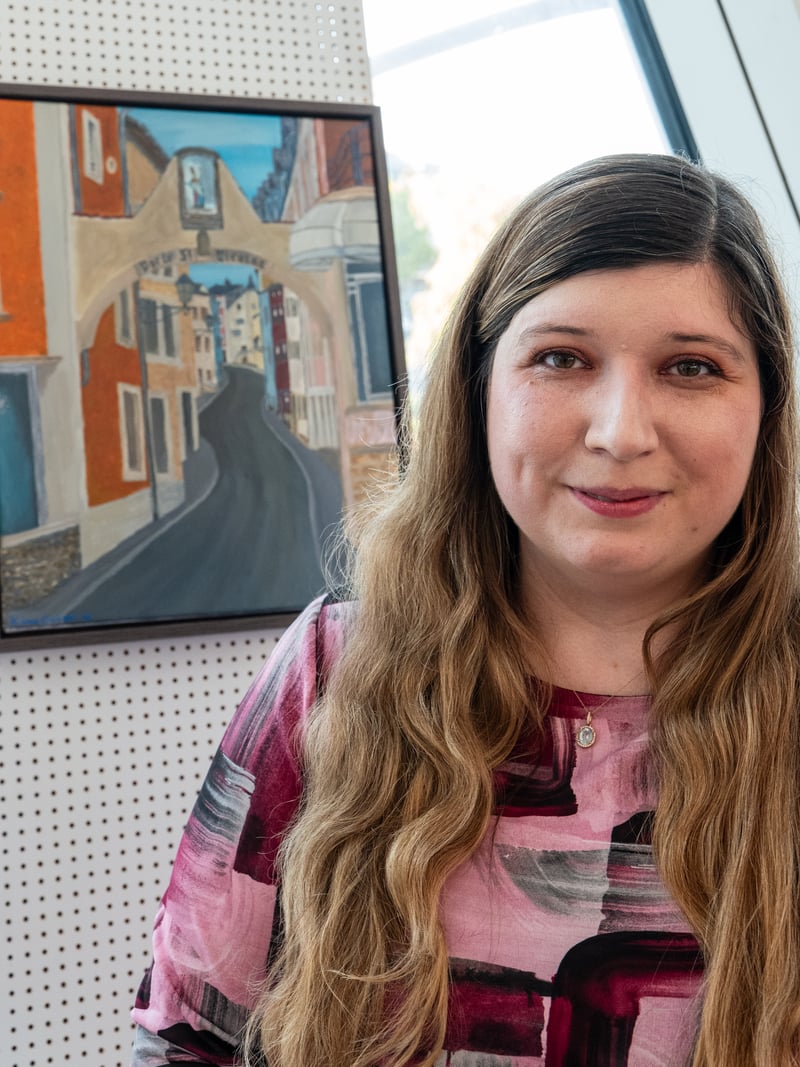 Kayleigh van Dongen beside her painting The Humble Gate, which shows the arch of the Porte St. Nicolas in Remich.